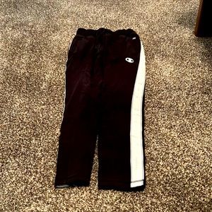 Black sweatpants with white strips on the side with the logo from Champion.